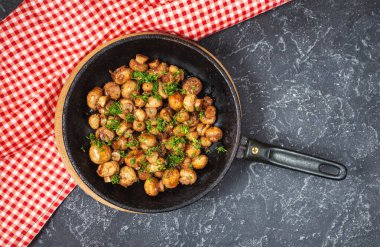 Siyah taş masadaki tavada nefis kızarmış mantarlar.
