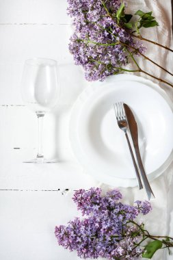 Bahar çiçekli bahar çiçek seti. Üst Manzara. Tabaklar, şarap kadehleri ve beyaz ahşap arka planda dekoratif tekstil..