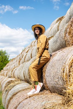 Samanlıkta tulumlu ve şapkalı genç bir kadın. Kırsalda tarlada kadın portresi.