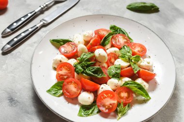 Geleneksel İtalyan Caprese Salatası - dilimlenmiş domates, mozzarella peyniri ve çimento üzerine fesleğen.