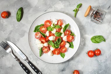 Geleneksel İtalyan Caprese Salatası - dilimlenmiş domates, mozzarella peyniri ve çimento arka planda fesleğen, üst manzara