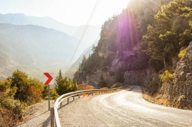 Kavisli Akdeniz asfalt yolu, güneşli bir günde tabela. Oludeniz, Türkiye.