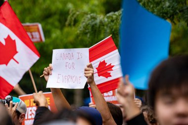 Kanada bayrağı taşıyan protestocuların manzarası ve üzerinde 
