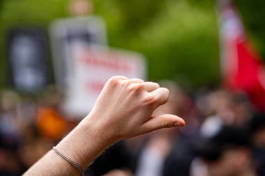 Protesto kalabalığında yükseltilmiş el hareketini kapat.