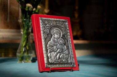 Kilisenin mihrabında Bakire Meryem ve Çocuk 'un gümüş simgesi olan dini kitap. Toronto, Kanada - 22 Ağustos 2025.