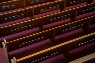 Kırmızı halıda ilahi kitapları olan boş ahşap kilise sıraları..