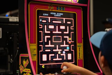 Player, bayan Pac-Man oyun makinesini oynamak için joystick kullanıyor. Toronto, Kanada - 16 Ağustos 2025.