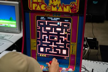 Oyuncu, Bayan Pac-Man 'in retro oyun dolabında eğleniyor. Toronto, Kanada - 16 Ağustos 2025.