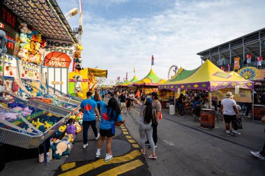 Kanada Ulusal Sergisi CNE 'de kalabalık ve doldurulmuş oyuncak ödülleriyle karnaval oyun standı manzarası. Toronto, Kanada - 16 Ağustos 2025.