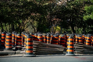 İnşaat alanında tahta tahtaları olan turuncu ve siyah varillerin yığılı görüntüsü.