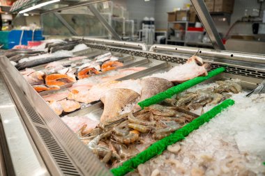 Süpermarkette balık filetosu, karides ve buzlu kabuklu deniz ürünleri sergileniyor..