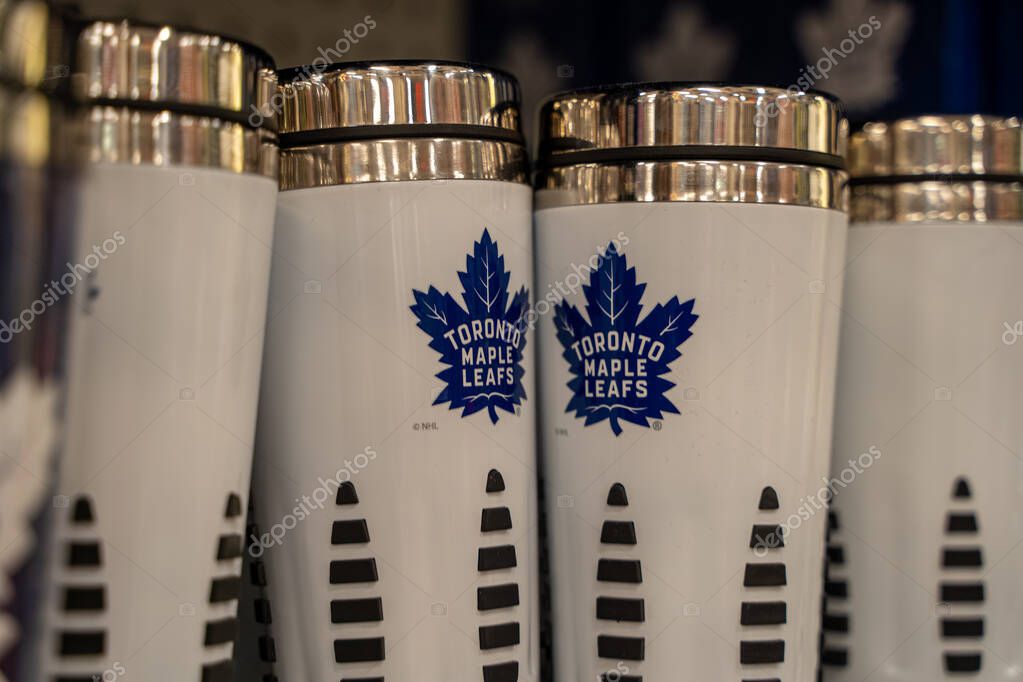 White Toronto Maple Leafs travel mugs with blue team logo on store shelf. Toronto, Canada - September 24, 2025.