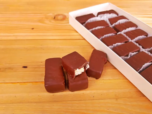 木製の背景のボックスに甘いチョコレートの盛り合わせ — ストック写真