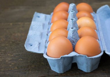 Tahta arka planda bir kutu tavuk yumurtası..