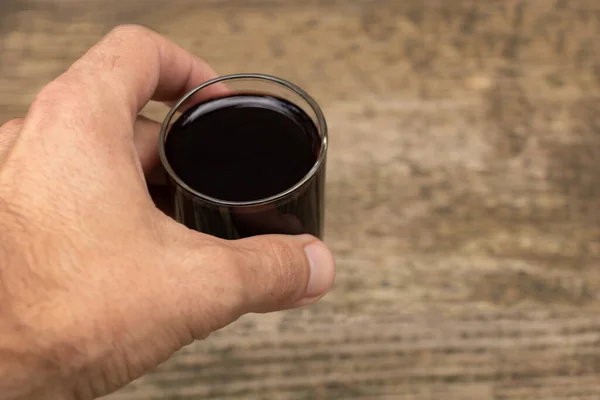A glass of red wine in a man's hand.
