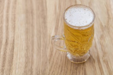 Ahşap arka planda bir bardak bira.