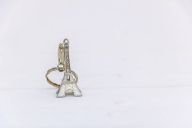 Eyfel Kulesi şeklinde metal anahtarlık. Beyaz arkaplanda Paris yazıtları izole edilmiş..