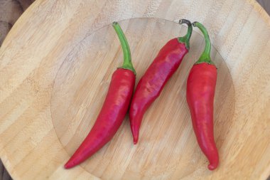 Tahta tabakta yeşil saplı taze kırmızı biber yakın plan, acı baharatlı sebze pişirme malzemesi..