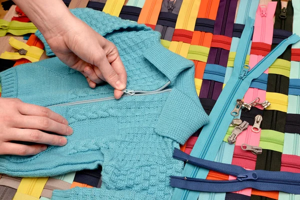 Fastening on a zipper a knitted sweater. Clothing repair. Checking the quality of fasteners on textile products