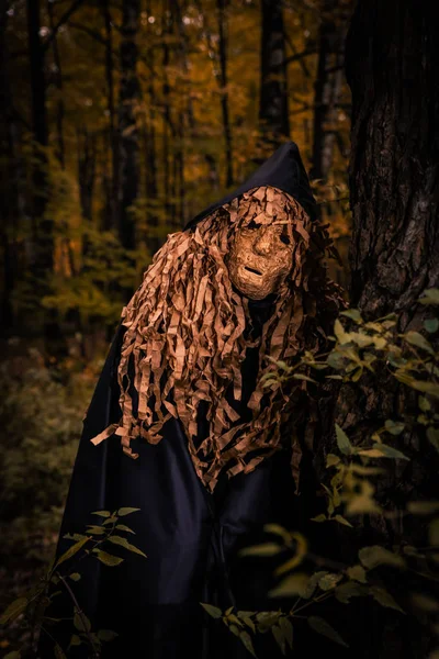 Man in a scary mask scarecrow in a cloak and with a hood