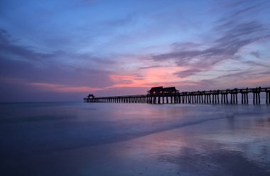 Pink and purple sunset over the Naples Pier in summer in Naples, Florida clipart