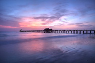 Pink and purple sunset over the Naples Pier in summer in Naples, Florida clipart