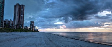 Yağmur dökülen karanlık bulutlar deniz tarağı Pass Beach Naples, Florida üzerinde günbatımında.