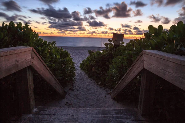 Boardwalk entrance of the Naples Beach at sunset with tropical plants in the summer in Naples, Florida