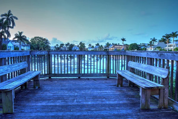 Secluded benches on a small deck overlooking a pond in Naples, Florida.