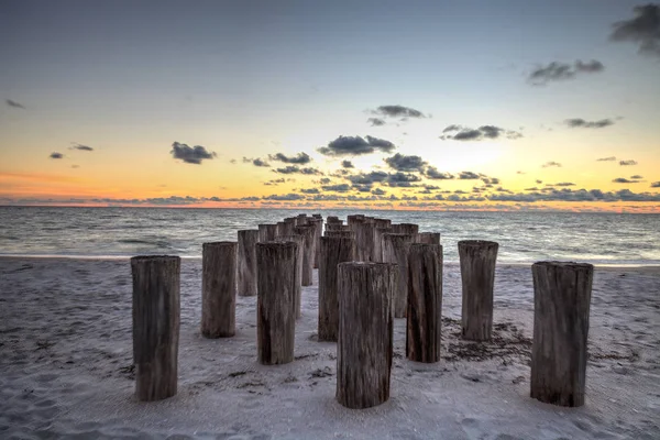 Dilapidated ruins of a pier on Port Royal Beach at sunset in Naples, Florida