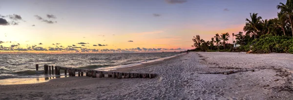 Dilapidated ruins of a pier on Port Royal Beach at sunset in Naples, Florida