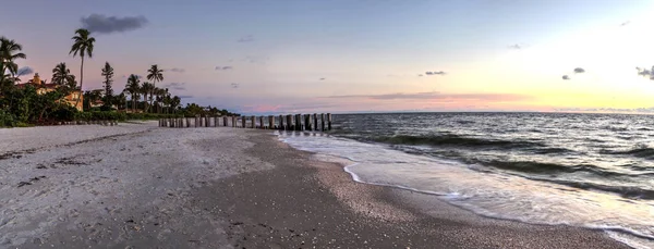 Dilapidated ruins of a pier on Port Royal Beach at sunset in Naples, Florida