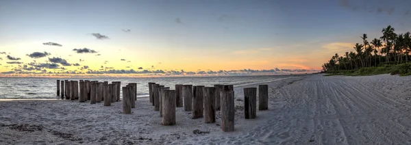 Dilapidated ruins of a pier on Port Royal Beach at sunset in Naples, Florida