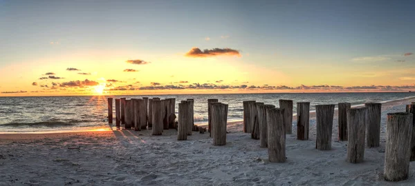 Dilapidated ruins of a pier on Port Royal Beach at sunset in Naples, Florida
