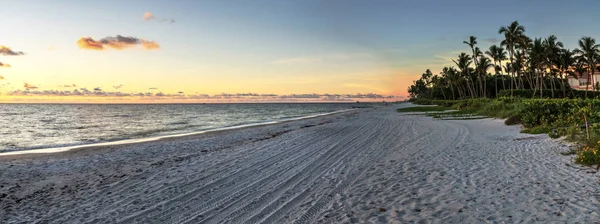 Dilapidated ruins of a pier on Port Royal Beach at sunset in Naples, Florida