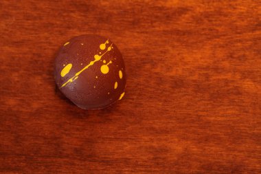 Zengin kremalı gurme, siyah ahşap arka planda lüks bir zanaatkar çikolatası..