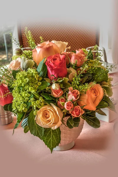 Pale peach roses, green hydrangea, and pink roses in a bouquet