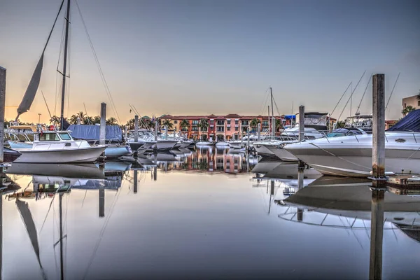 Soluppgång över en hamn med segelbåtar och färgglada byggnader — Stockfoto