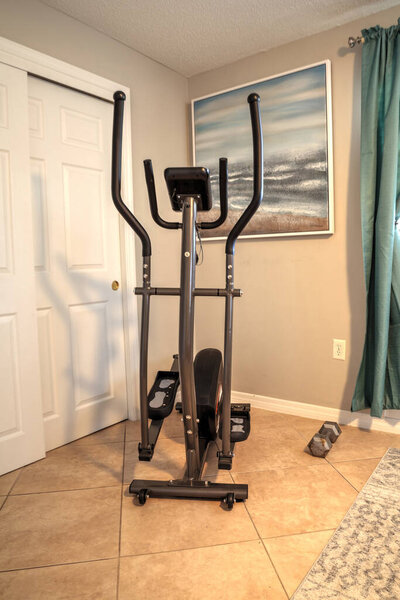 Эллиптическая машина в домашнем тренажерном зале для домашних упражнений и физической подготовки.