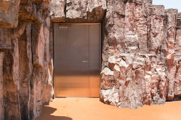 Closed door stainless with wall of rock surface texture.