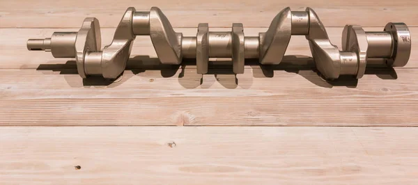 Engine crankshaft on wooden plank with copy space.