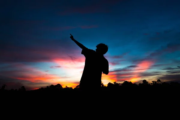 Silhouette of a male holding hands at sunrise, and happy winning