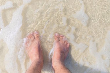 Deniz köpüğünde ıslak kumda iki çıplak ayak. yaz arkaplanı.