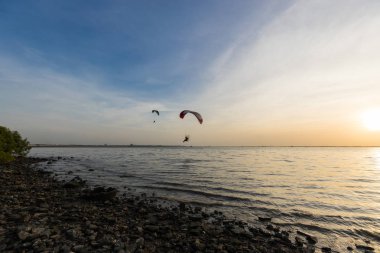 Gün batımında gökyüzüne uçan Paramotor silueti.