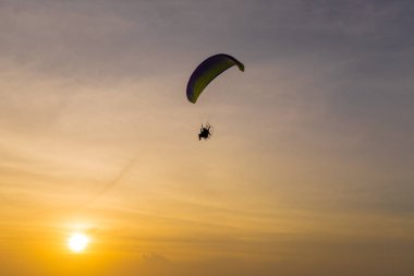Gün batımında gökyüzüne uçan Paramotor silueti.