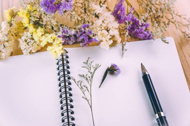 Ahşap masa üstünde boş defter koymak çiçek çiçek