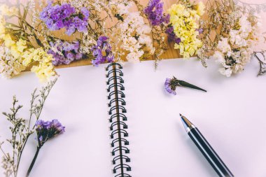 Ahşap masa üstünde boş defter koymak çiçek çiçek