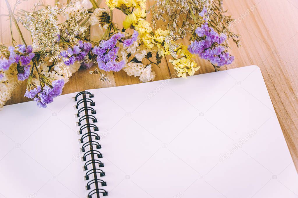 Flower blossom put on blank notebook, on wooden table