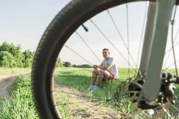 Człowiek Siedzi Trawie Koła Rowerowego — Zdjęcie stockowe