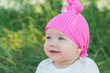 Gülümseyen çocuk çim pembe şapkalı. Şapka polka noktaları. Yeşil çim. Gülümseyen çocuk.